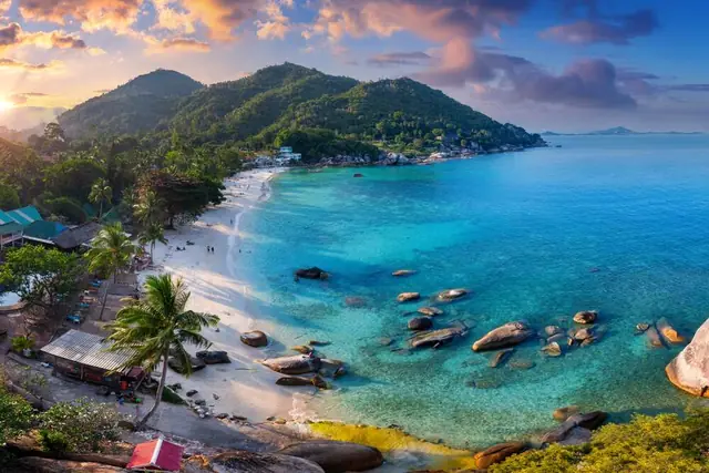 Silver Beach, Koh Samui — white sand cove with granite boulders, palm trees and clear turquoise shallows at golden hour