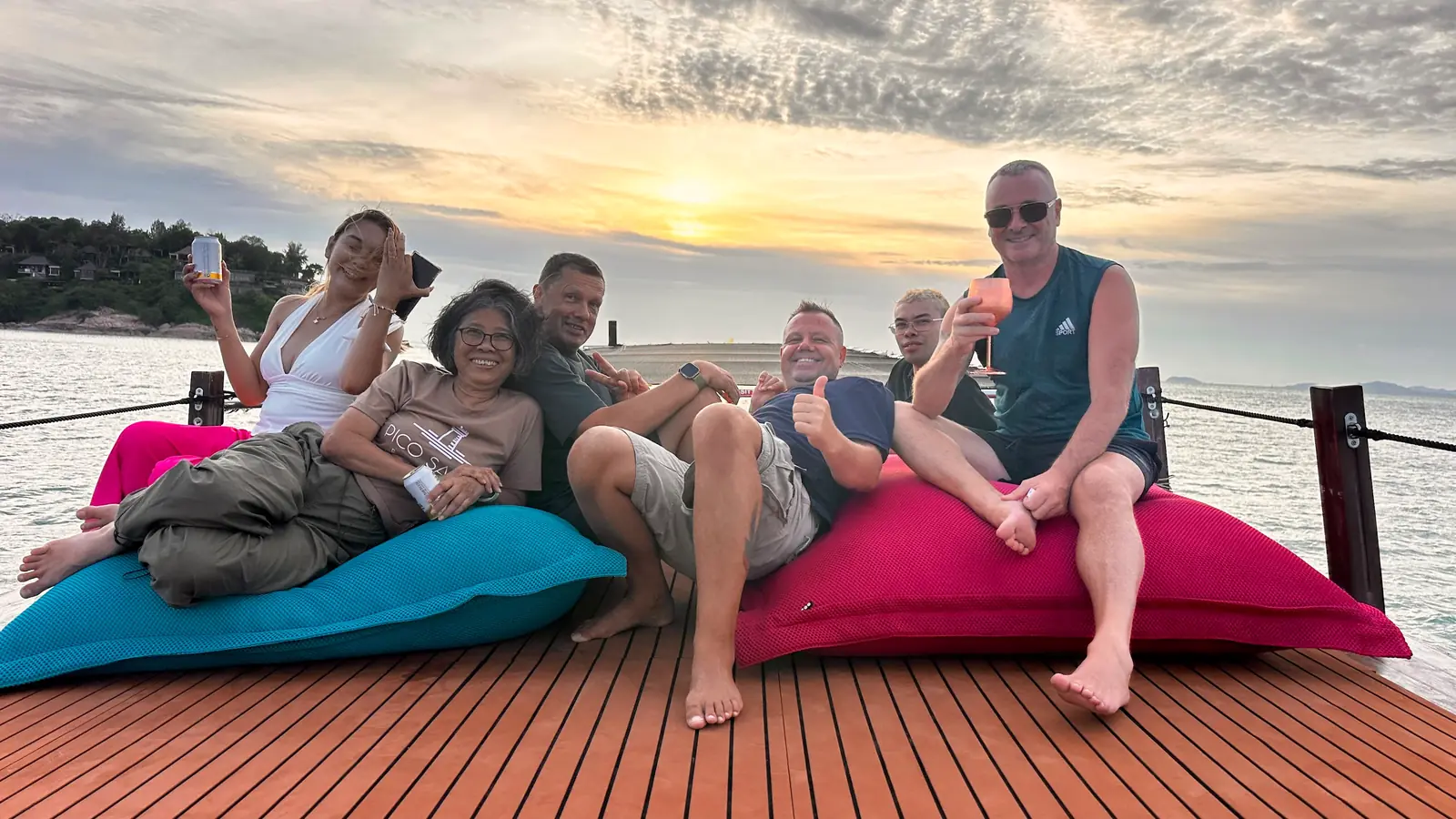 Guests relaxing on colourful rooftop beanbags of the Endless Summer at golden hour on the Sunset Cruise