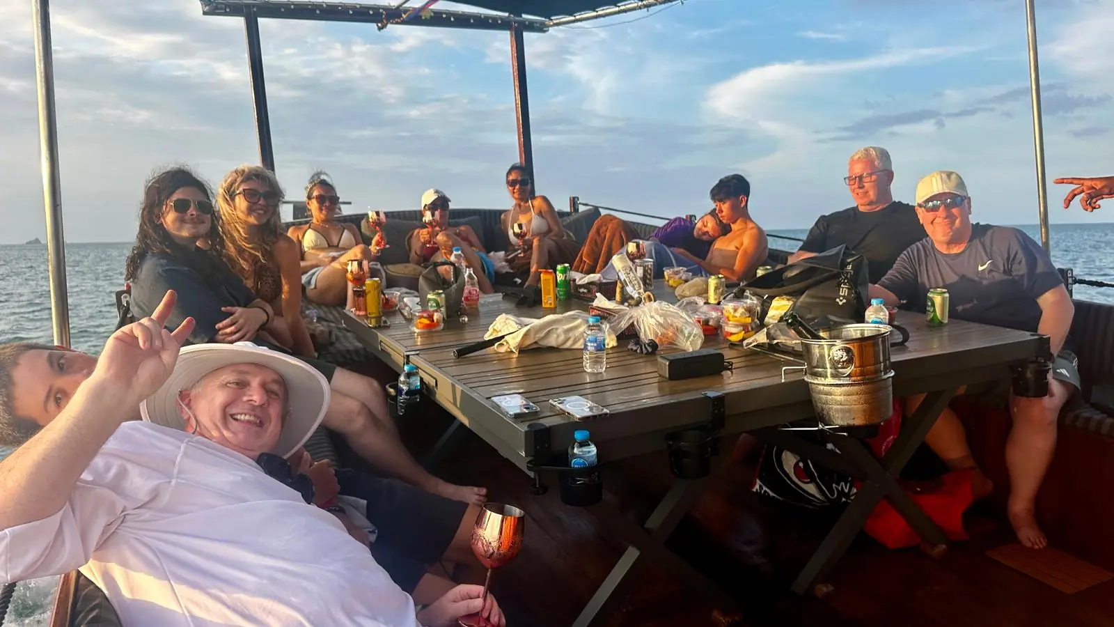 Guests relaxing around the long wooden deck table of the Endless Summer at golden hour