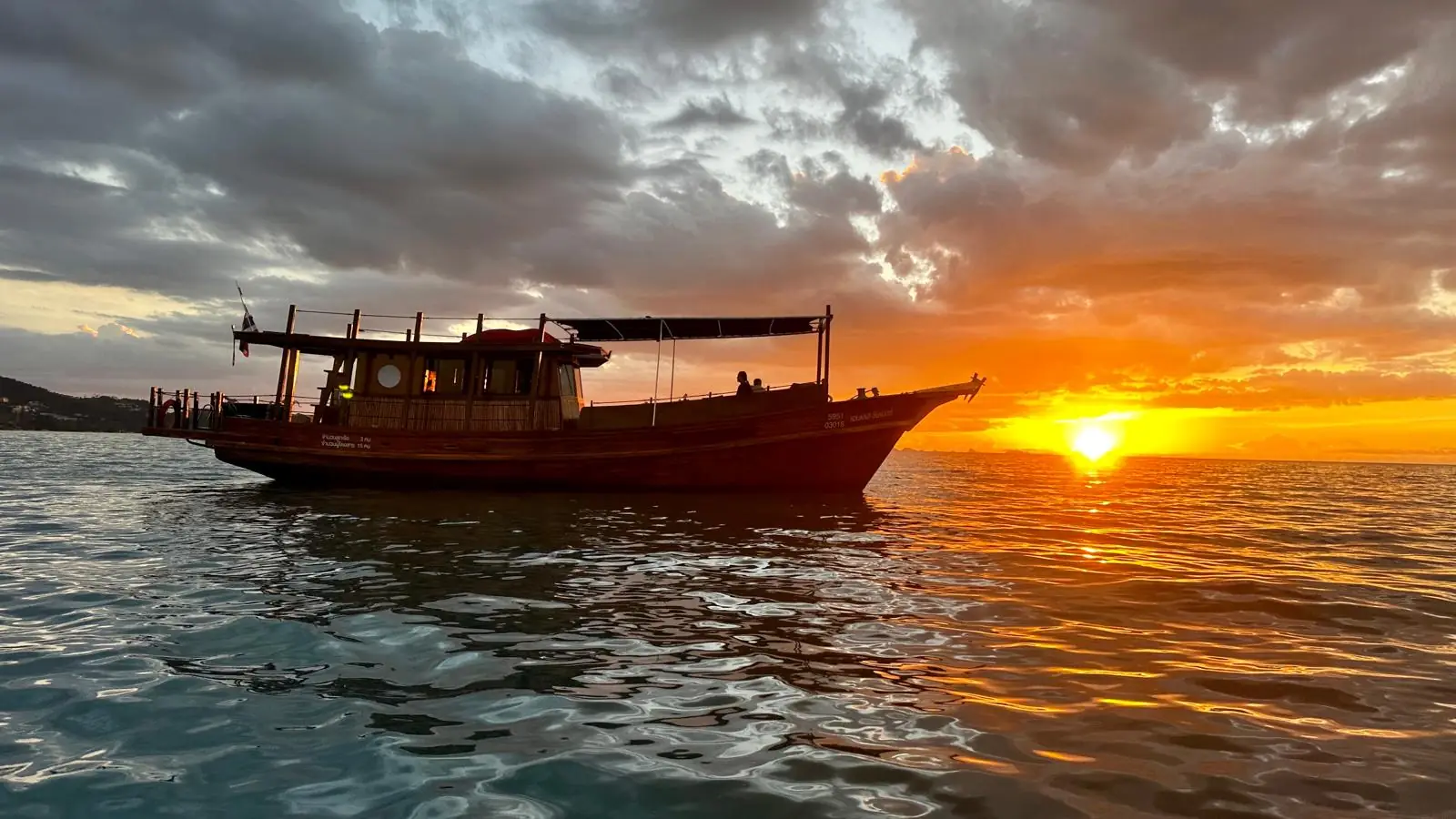The Endless Summer Thai teak cruiser silhouetted against a fiery orange Koh Samui sunset over the Gulf of Thailand