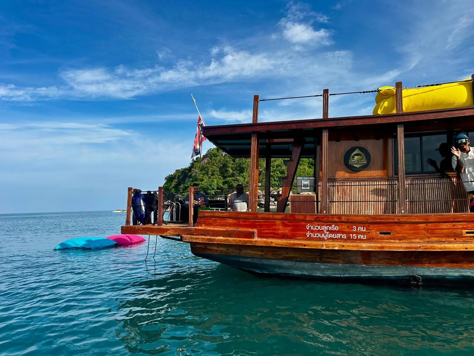 Endless Summer's handcrafted Thai teak cruiser anchored in turquoise water, an island behind